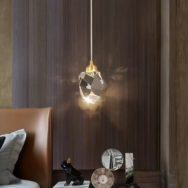 Luminária Pendente LED Cristal Lapidado Gold Larevy acesa em ambiente de quarto com paredes escuras e cabeceira marrom