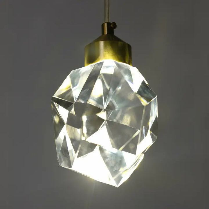 Luminária Pendente LED Cristal Lapidado Gold Larevy iluminada contra fundo cinza, destacando brilho interno
