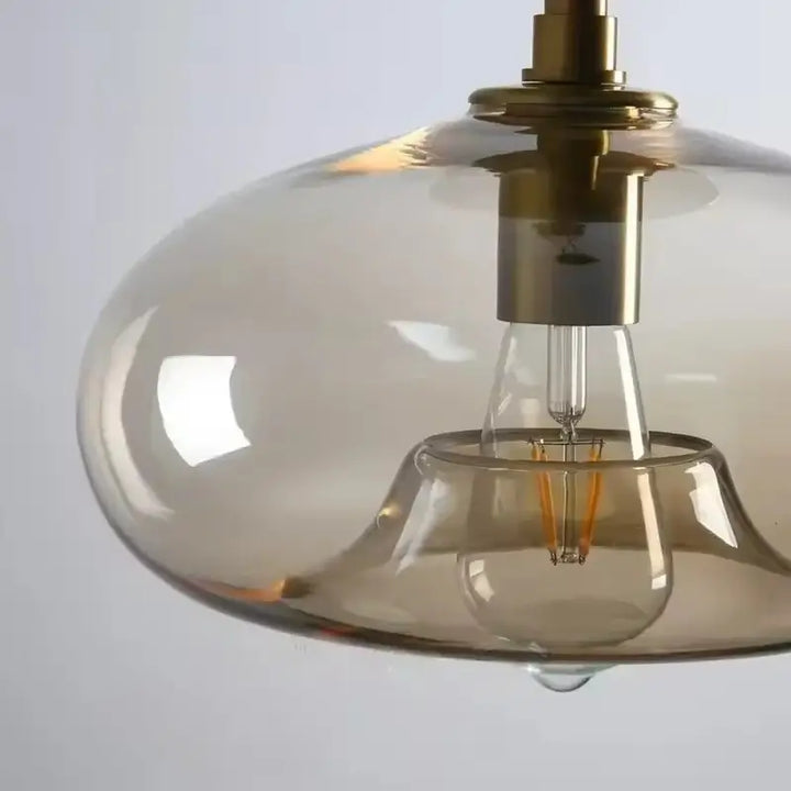 Close-up da Luminária Pendente Vidro Ambaris Ápice destacando vidro translúcido e lâmpada filamento LED