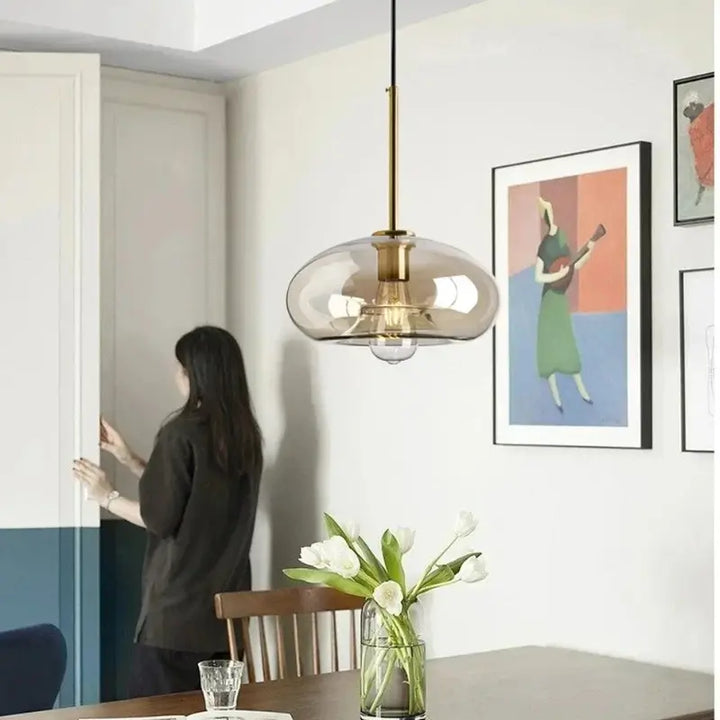 Luminária Pendente Vidro Ambaris Ápice com acabamento bronze dourado sobre mesa de jantar em ambiente decorado