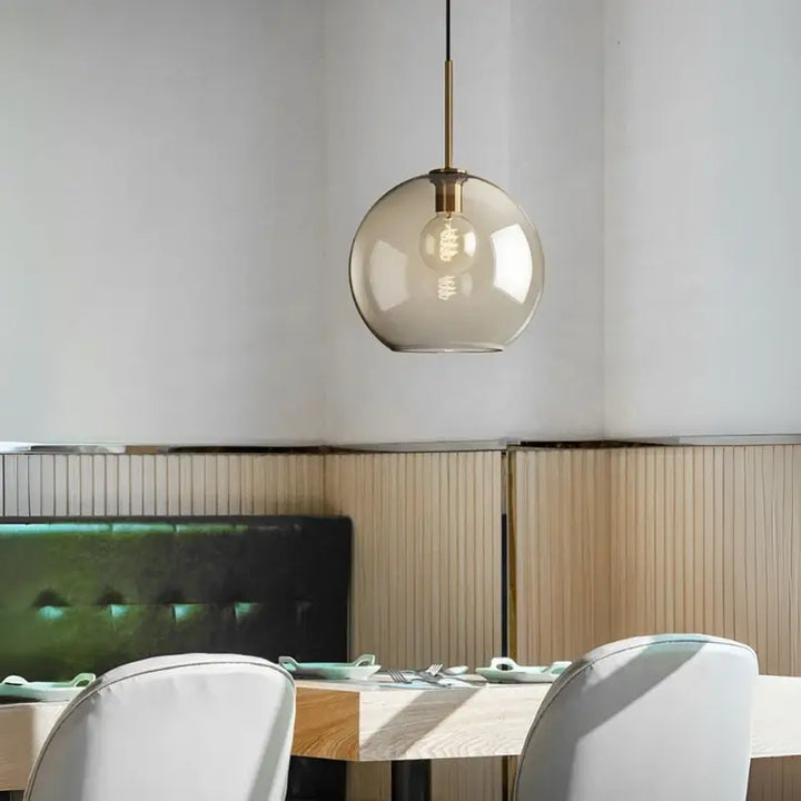 Luminária Pendente Vidro Ambaris Magna em ambiente de restaurante com banco estofado verde e revestimento amadeirado