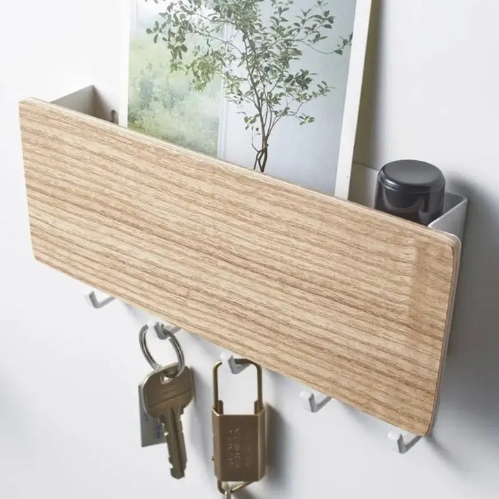 Porta chaves Orto madeira clara instalado na parede com chaves penduradas e objetos no compartimento superior