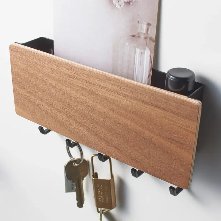 Porta chaves Orto madeira escura instalado na parede com chaves penduradas e objetos no compartimento superior