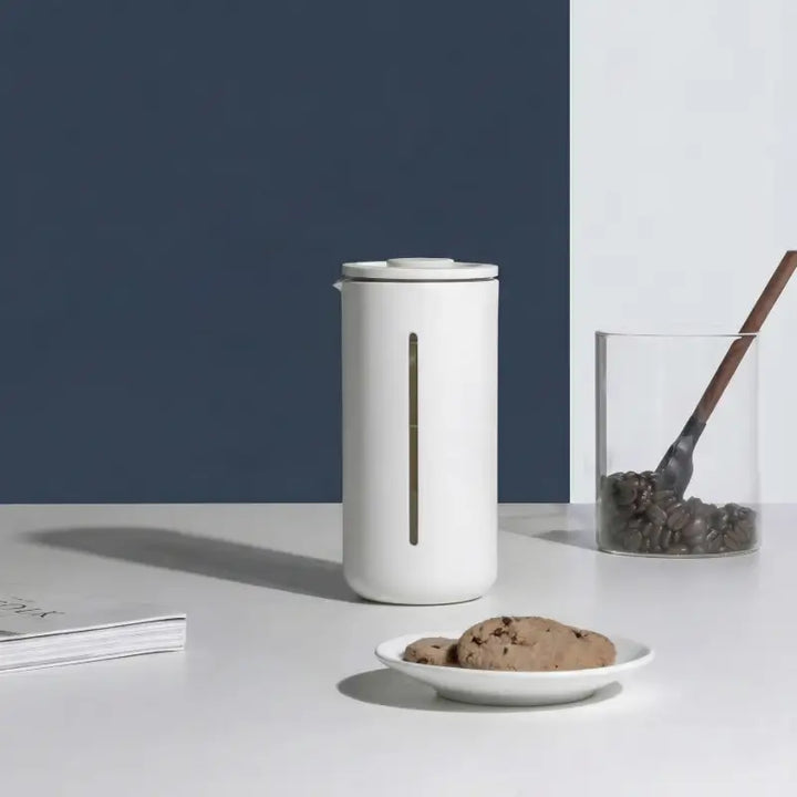 Cafeteira Prensa Francesa 450 ml Timemore U Branco na bancada com biscoitos e pote de grãos de café.